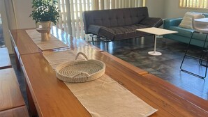 Une longue table en bois, avec un panier tressé et un tapis beige.