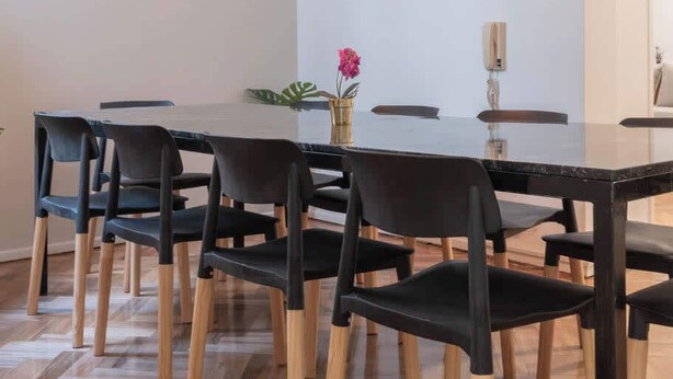 Een eetgedeelte met een ronde tafel, zwarte stoelen en een hanglamp.