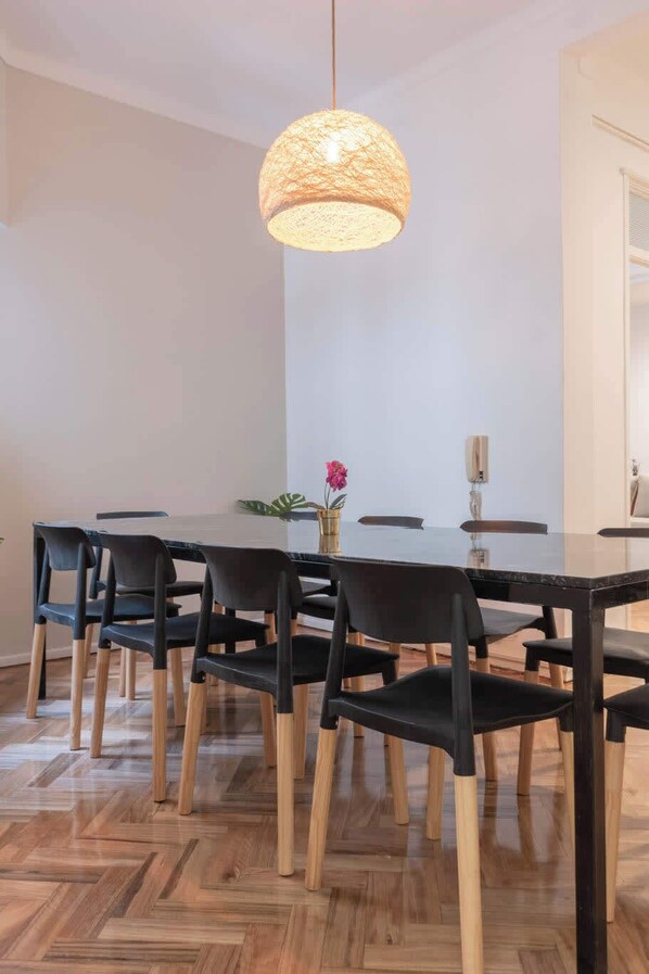 A dining area with a round table, black chairs, and a hanging light fixture.