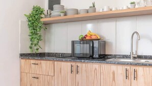 Een keuken met houten kastjes, een magnetron, een spoelbak en een fruitschaal op het aanrecht.
