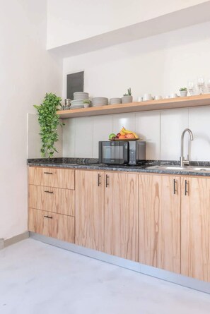 Una cocina con armarios de madera, un microondas, un lavabo y un frutero sobre la encimera.