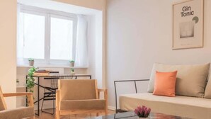Een moderne woonkamer met een bank, stoelen, een glazen salontafel en een eethoek met een tafel en stoelen.