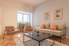 Una sala de estar moderna con un sofá, dos sillones, una mesa de centro y una zona de comedor con mesa y sillas.