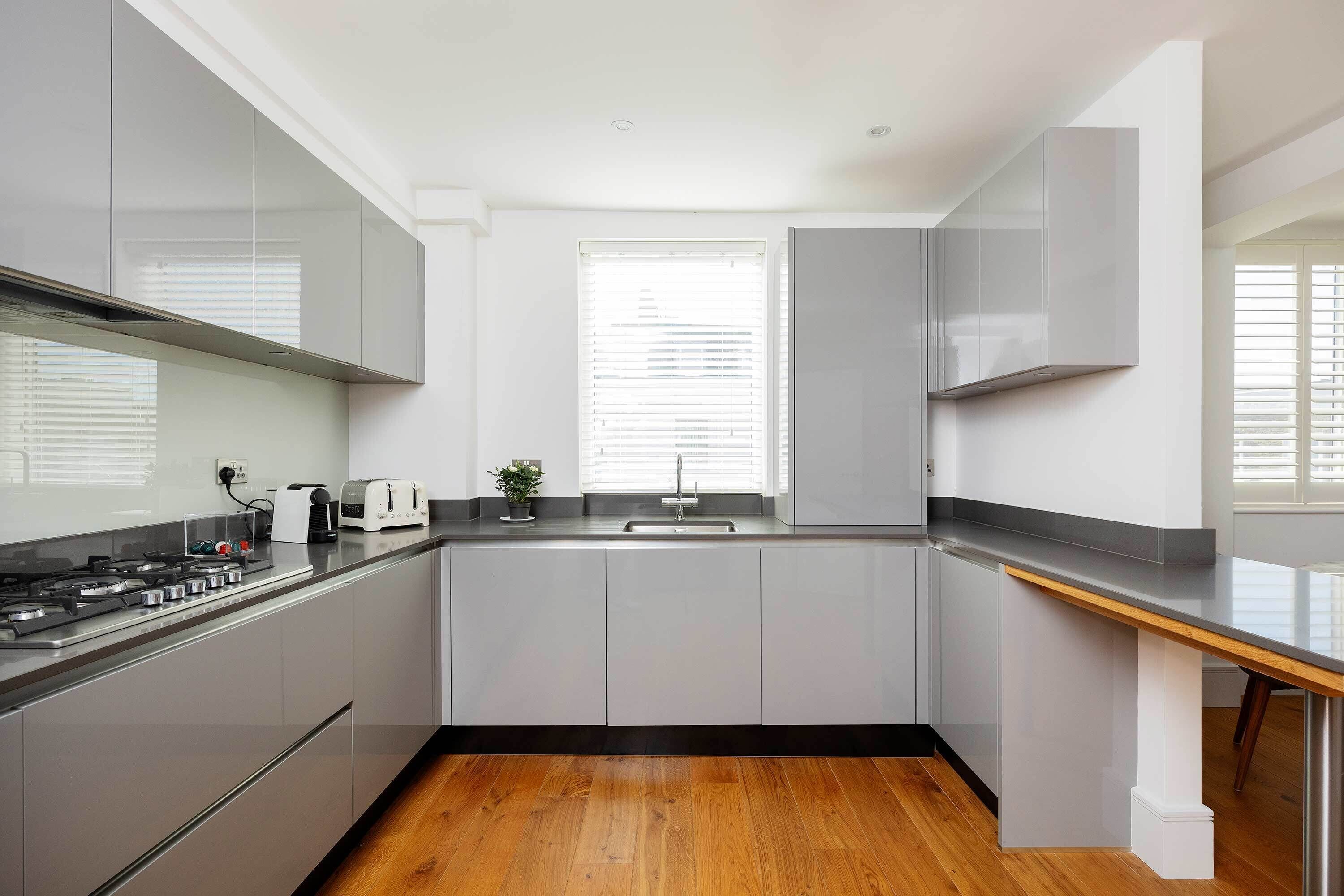 A modern kitchen with a central island, stainless steel appliances, and a window with blinds.
