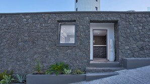 A modern building with a stone facade, a small window, and a door leading to an interior space. - Topos Exclusive Santorini (Santorini)
