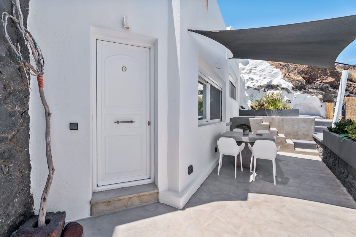 A white building with a door, outdoor seating, and a view of a snowy landscape.