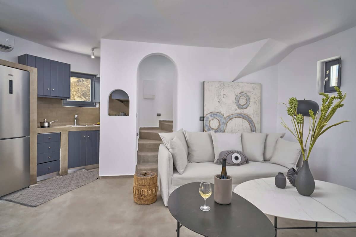 A modern living space with a kitchen, a sofa, a coffee table, and a painting on the wall.