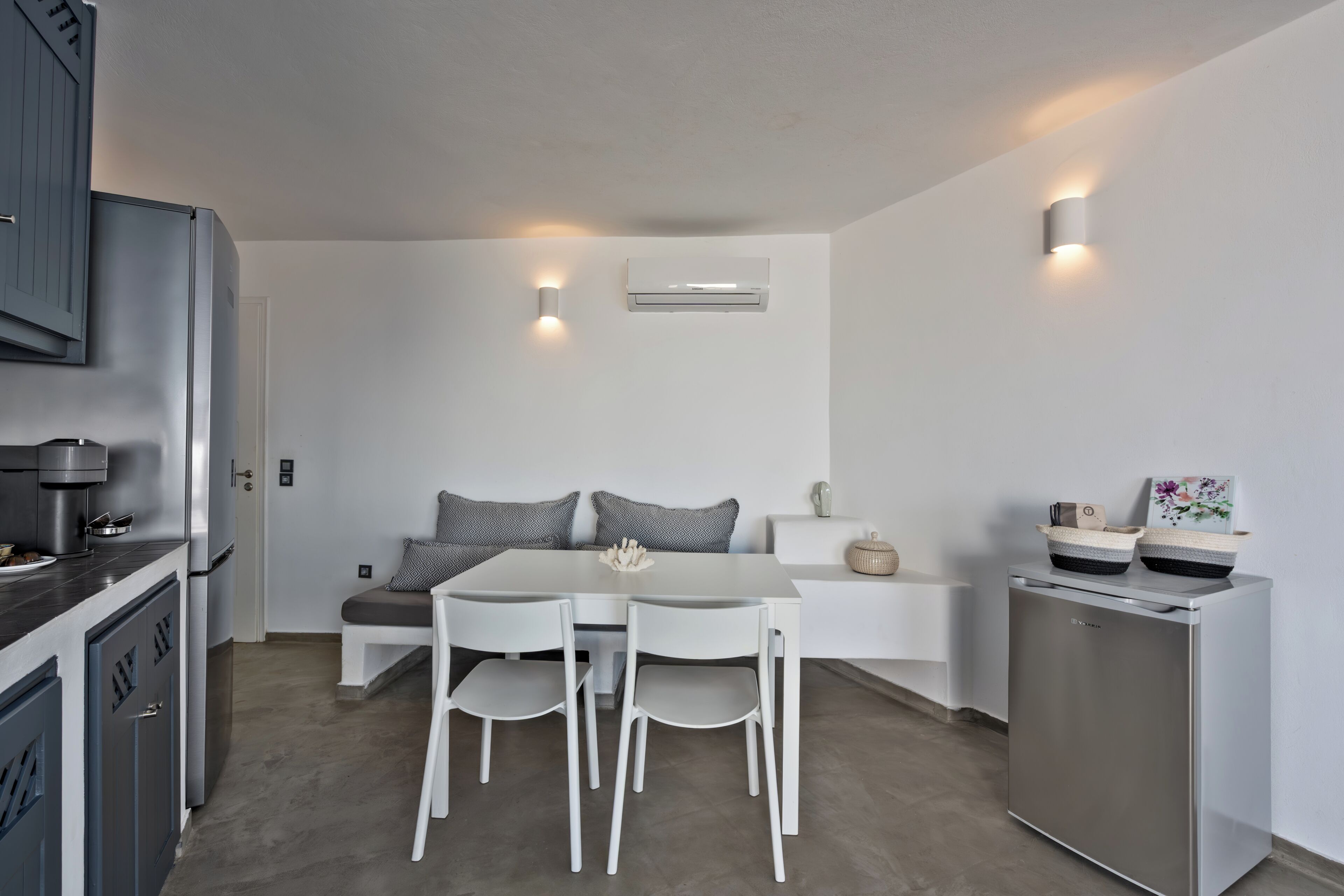 A modern kitchen with a dining table, chairs, a refrigerator, and a built-in oven.