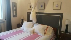 A neatly made bed with a striped bedspread, a headboard, and two bedside lamps. - Lovely Flat at Grado Pineta (Grado)