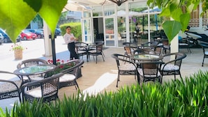 An outdoor patio area with wicker furniture and a glass door entrance. - HOTEL DELTA (Constanta)