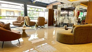 Un hall d’entrée spacieux, doté d’un sol ciré, de sièges confortables, d’une cheminée et de grandes fenêtres offrant une vue sur l’extérieur.
