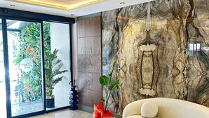 Un intérieur moderne avec un mur en marbre, un canapé et une petite table agrémentée d’une plante.