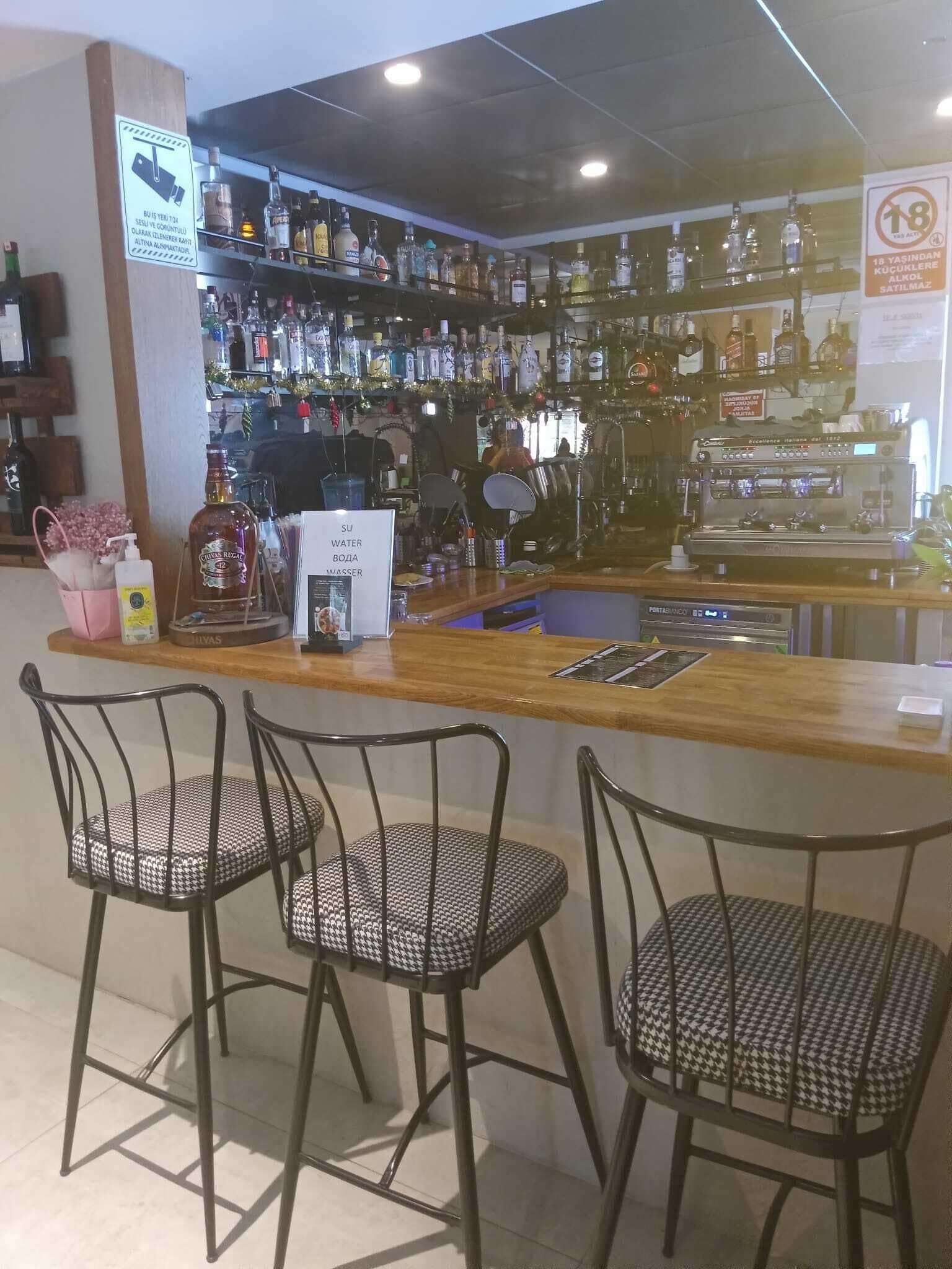 Eine Bar mit einer Theke, Stühlen und einer Auswahl an Flaschen.