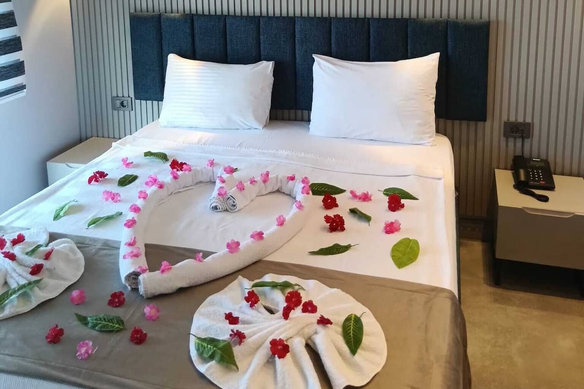 A hotel room with a bed, pillows, a headboard, bedside tables, and a phone.