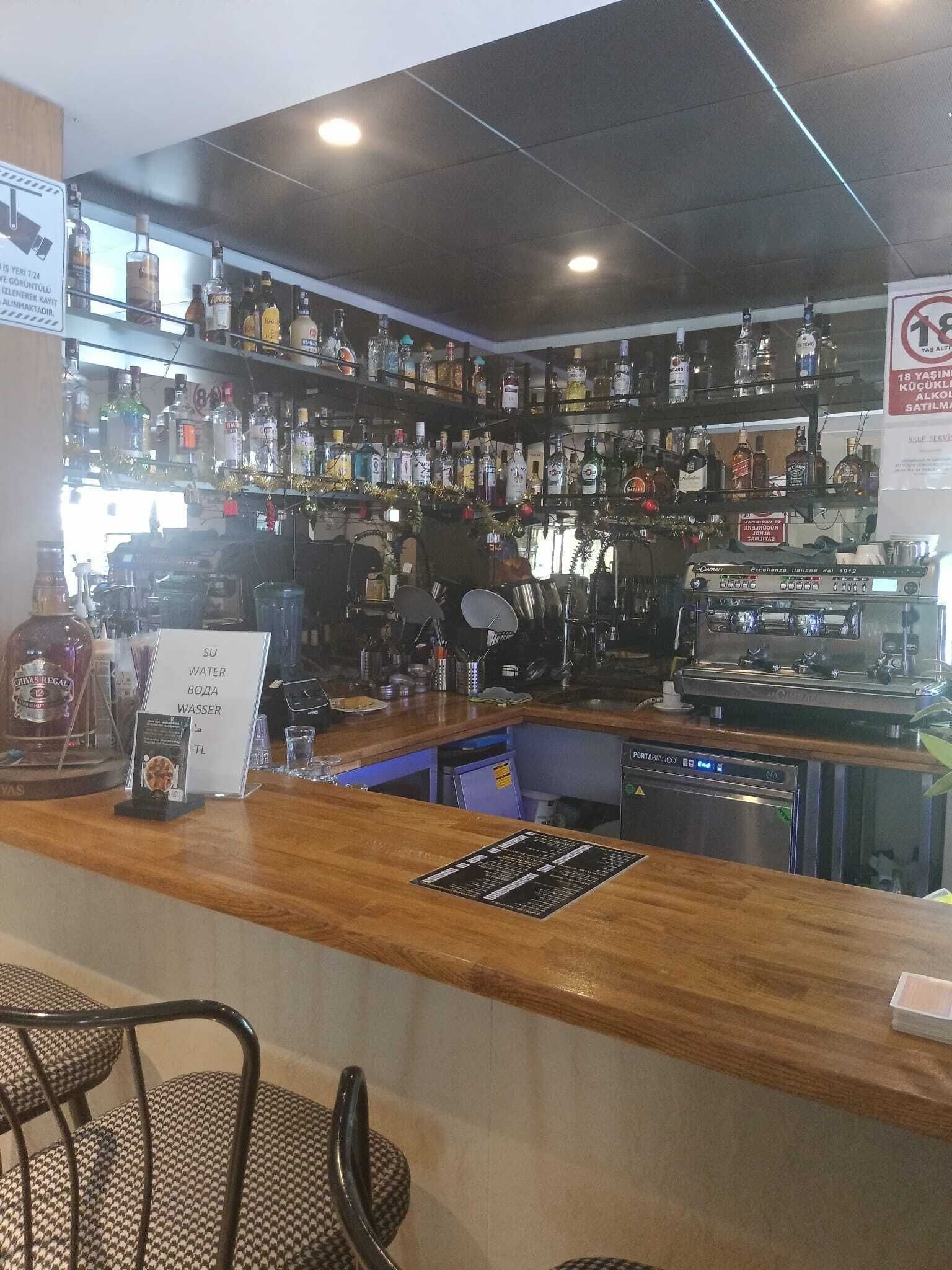 A bar area with shelves of liquor bottles, a coffee machine, and a sign indicating water availability.