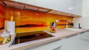 Una cocina moderna con una placa de inducción integrada, un bol de vidrio con frutas y un dispensador de toallas de papel.