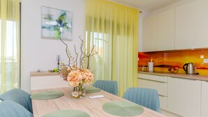 Una cocina moderna con una cortina amarilla, un jarrón con flores y un cuadro en la pared.