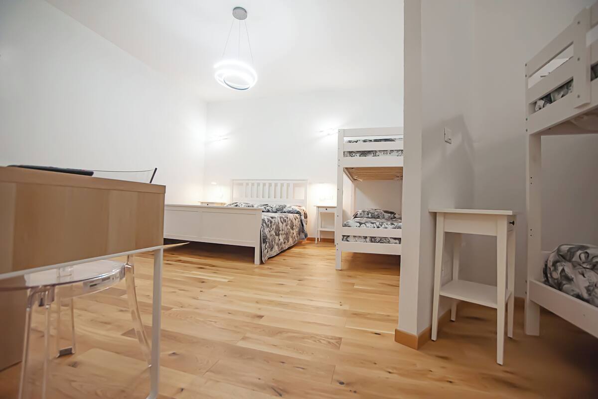 A bedroom with bunk beds, a desk, and a chair.