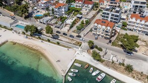 An aerial view of a coastal area with buildings, a beach, and boats. - Apartment Rizza (Trogir)