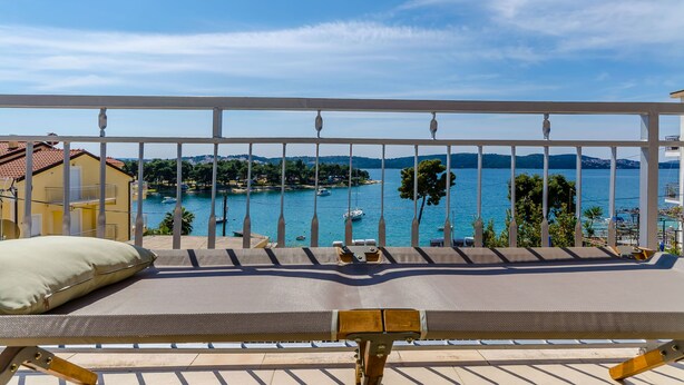 A balcony with a view of a coastal area, including boats and buildings. - Apartment Rizza (Trogir)