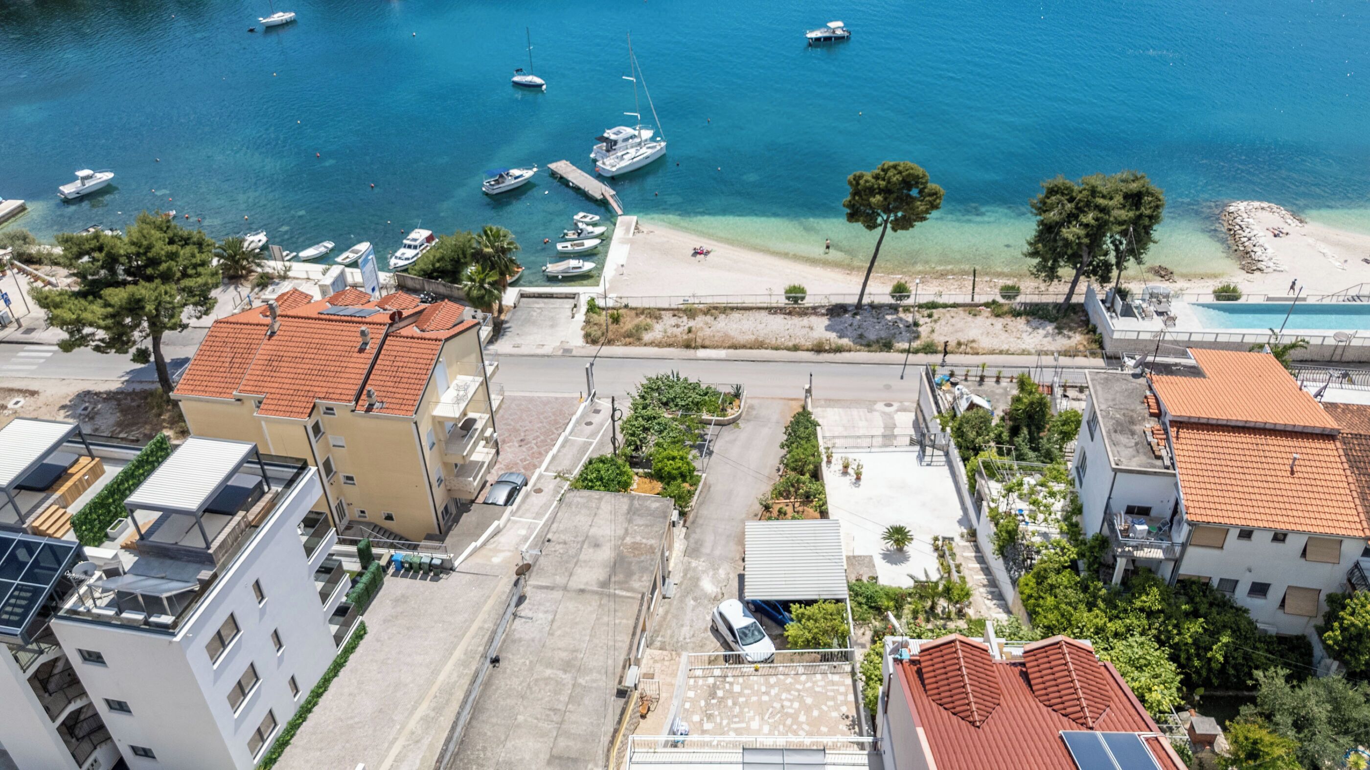 An aerial view of a coastal town with buildings, a beach, and boats.
