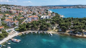 An aerial view of a coastal town with residential buildings, a marina, and clear blue waters. - Apartment Rizza (Trogir)