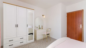 A bedroom with a large wardrobe, a vanity with a mirror, a wooden door, and a bed. - House Zdenka (Okrug Donji)