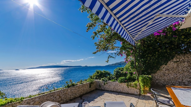 A patio with a view of the sea, stone walls, and outdoor furniture. - House Zdenka (Okrug Donji)