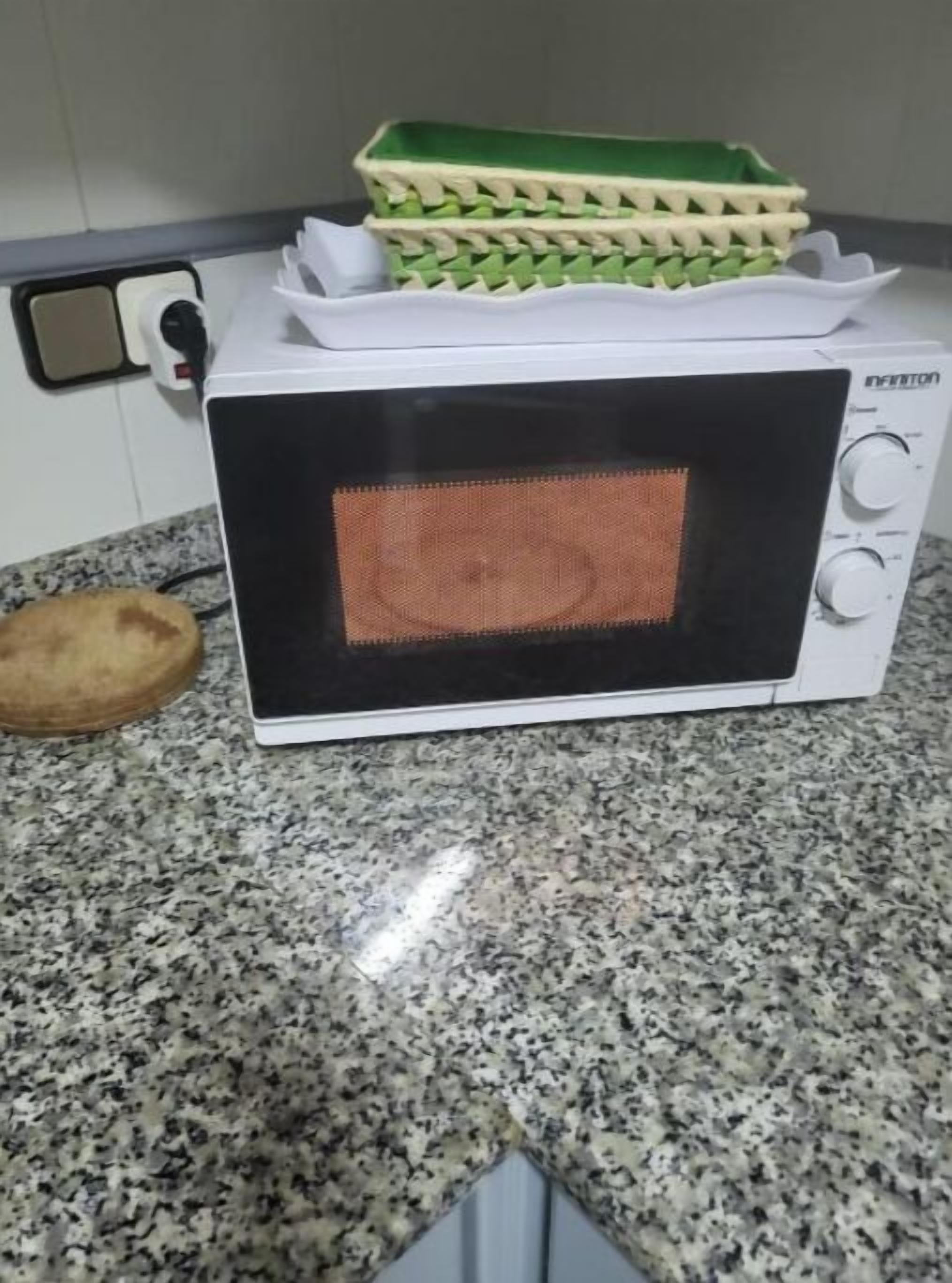 A white microwave oven with a digital display on a granite countertop.