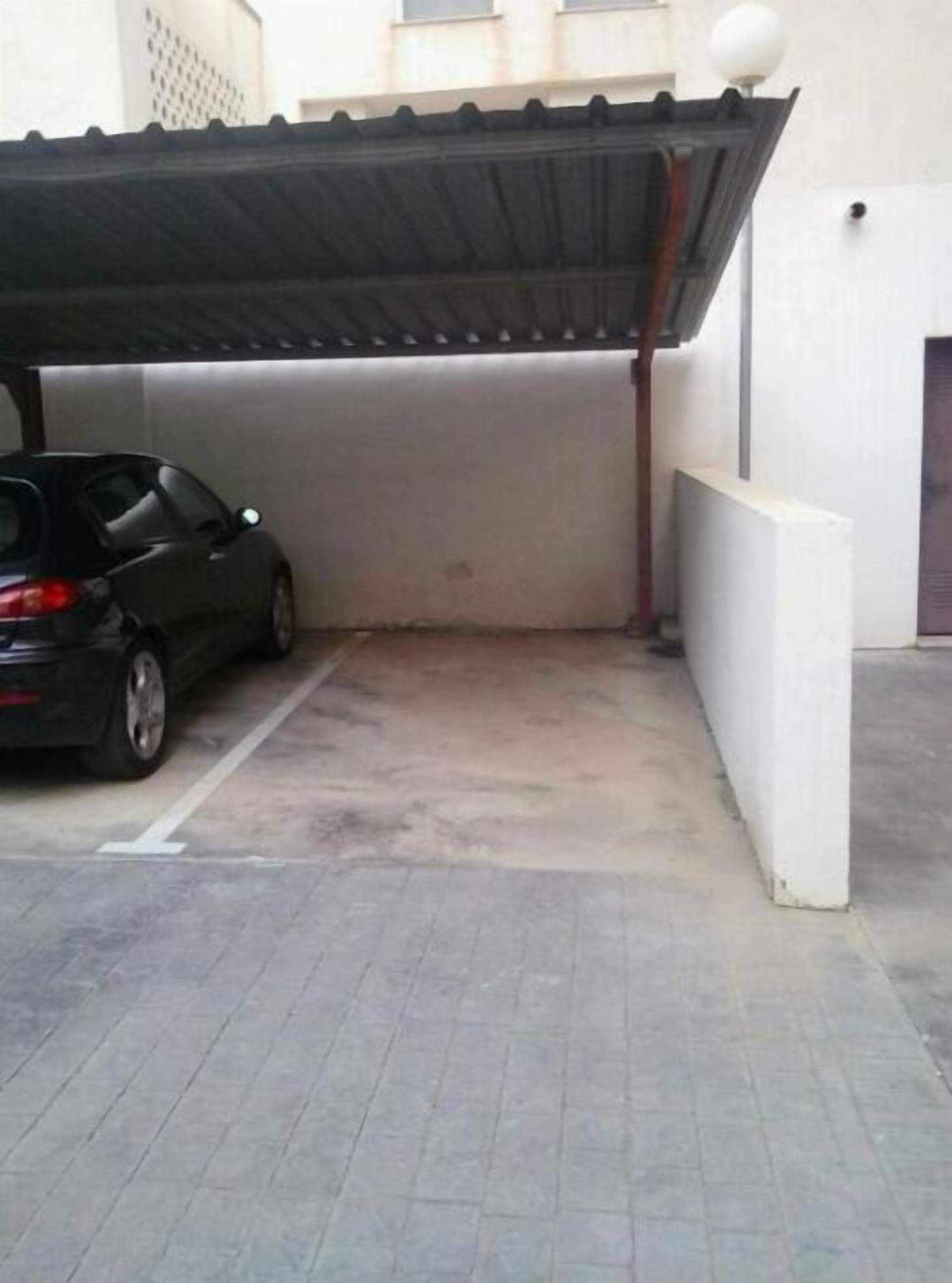 A parking area with a car parked under a covered section.