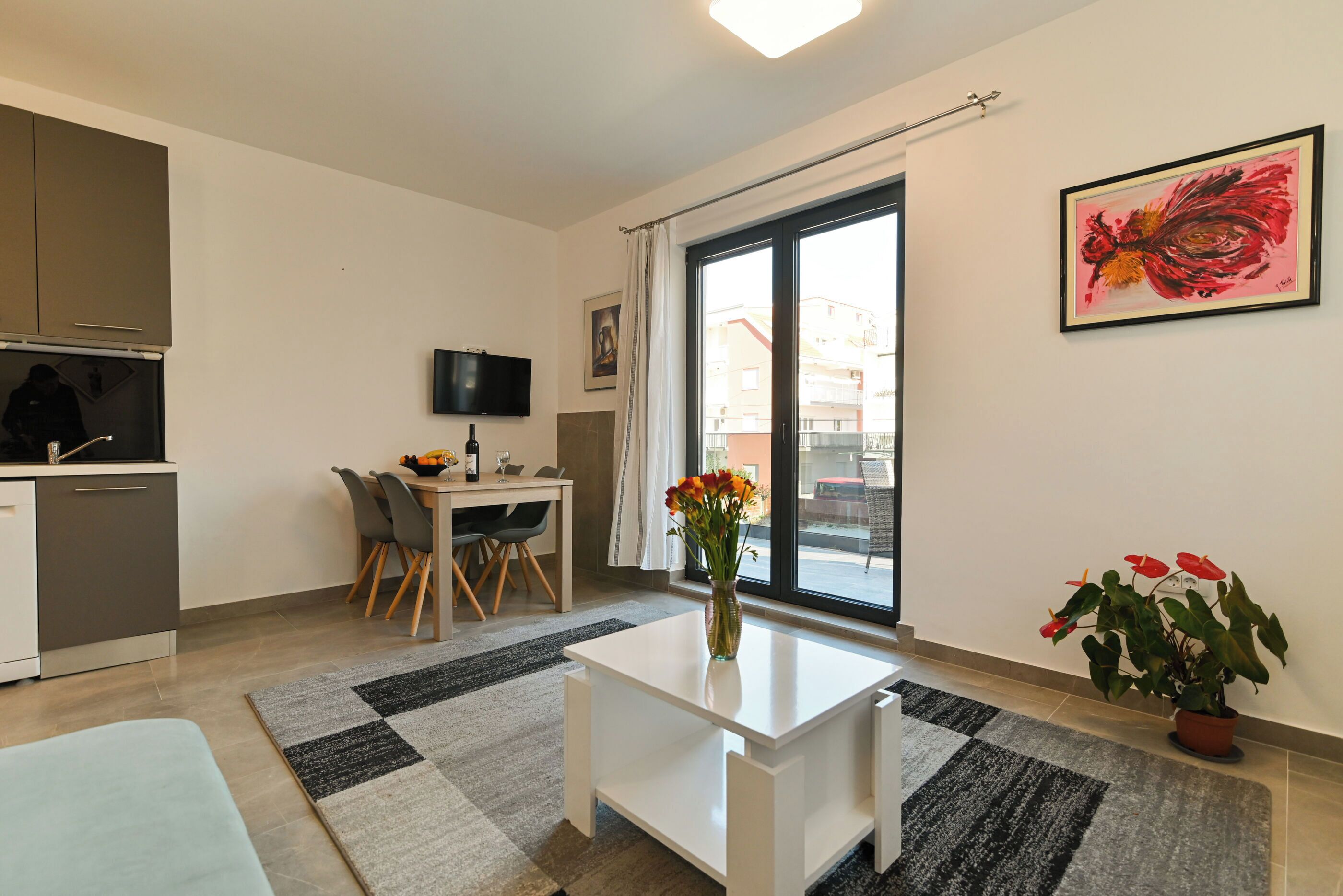 A modern apartment with a kitchen, dining area, and a large window.