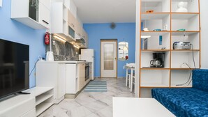 A compact living space with a kitchen, a TV, a sofa, and a bookshelf. - Apartments Helios (Kastel Gomilica)
