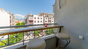 A balcony with two chairs and a heart-shaped decoration, overlooking a row of buildings and greenery. - Apartment Dora (Trogir)