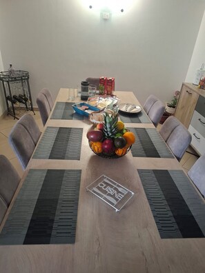 A dining table with a fruit bowl, placemats, and a 'CUISINE' sign. - Apartment Dora (Trogir)