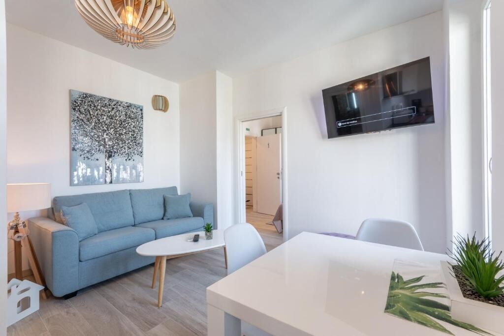 Ein modernes Wohnzimmer mit einem blauen Sofa, einem weißen Couchtisch und einem an der Wand befestigten Flachbildfernseher.