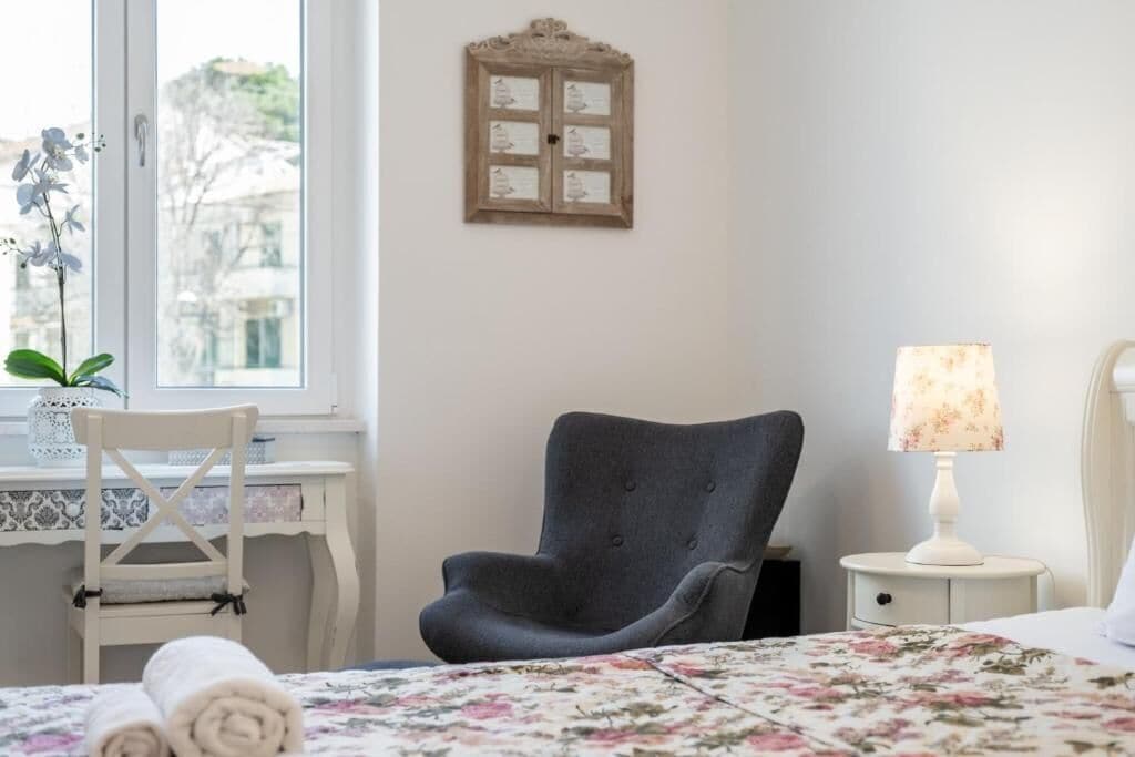 Une chambre avec un lit, une chaise, un bureau, une lampe et une fenêtre donnant sur un beau paysage.