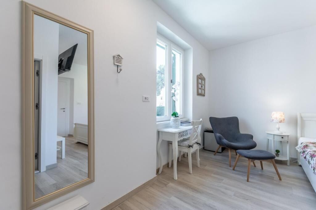 Une chambre avec un grand miroir, un bureau avec une chaise, un lit et une fenêtre.