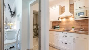A modern kitchen with white cabinets, a wooden countertop, and a built-in microwave. - Apartments and Room Poesia (Split)