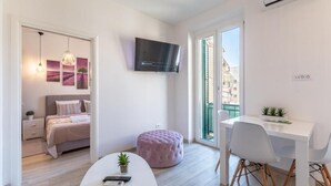 A modern bedroom with a bed, bedside table, and a TV mounted on the wall. - Apartments and Room Poesia (Split)