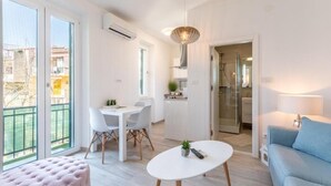 A modern apartment with a dining area, kitchen, and a balcony with a view of buildings. - Apartments and Room Poesia (Split)