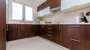 Een moderne keuken met donkere houten kastjes, een wit aanrechtblad en een raam dat voor natuurlijk licht zorgt.