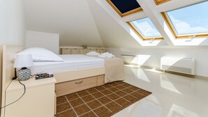 Een moderne slaapkamer met dakraam, een bed, een nachtkastje met lamp en een radiator.
