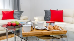 A modern living room with a sofa, coffee table, and breakfast items. - Apartment Gilda Lux (Split)