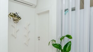 A white door with a keyhole, a wall-mounted air conditioner, and a decorative mask. - Apartment Anni (Okrug Gornji)