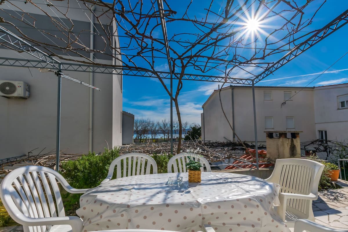 An outdoor patio with a round table covered with a polka dot tablecloth, surrounded by white chairs.