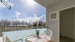 A balcony with a table and chairs, overlooking a body of water and trees. - Apartments Ivanka (Duce)