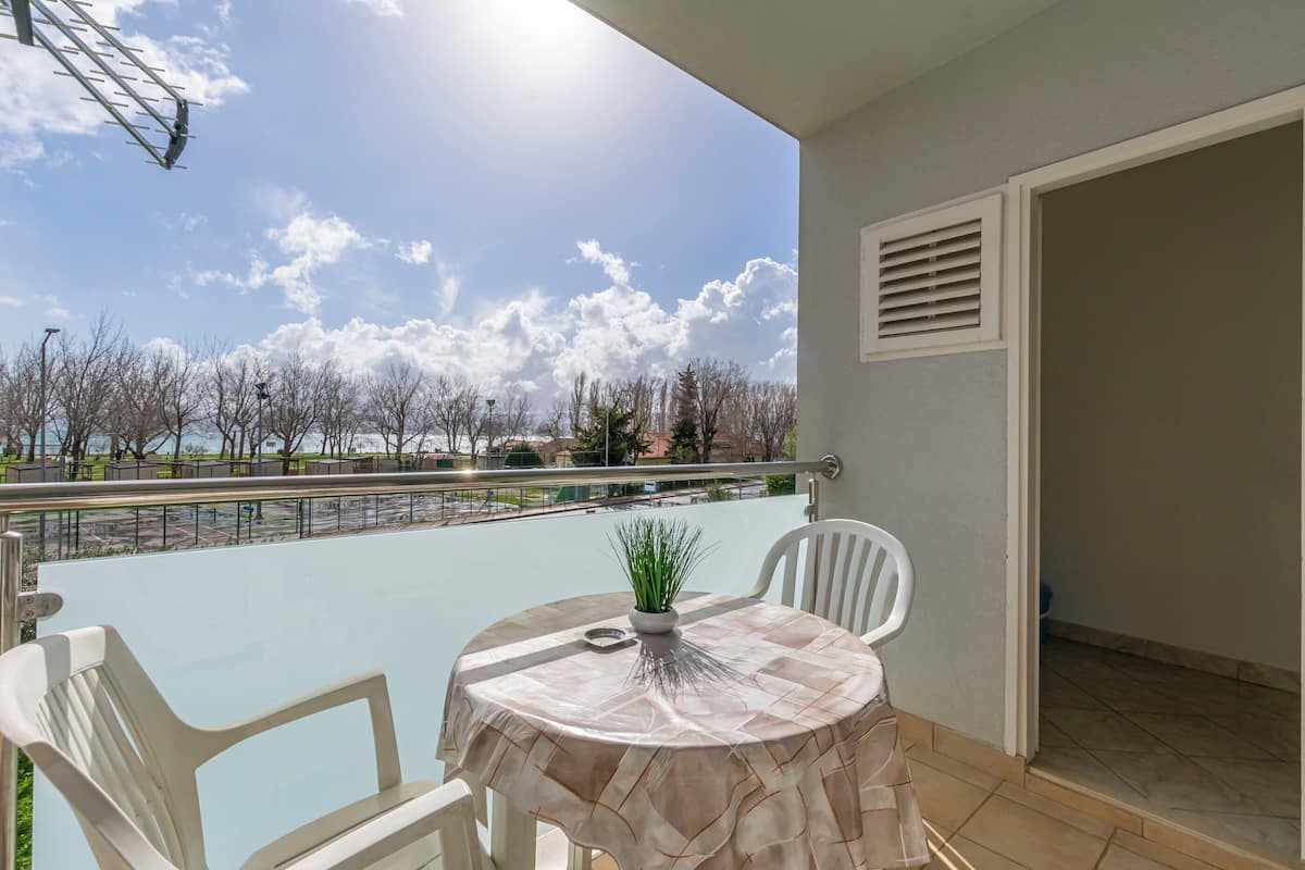 A balcony with a table and chairs, overlooking a body of water and trees.