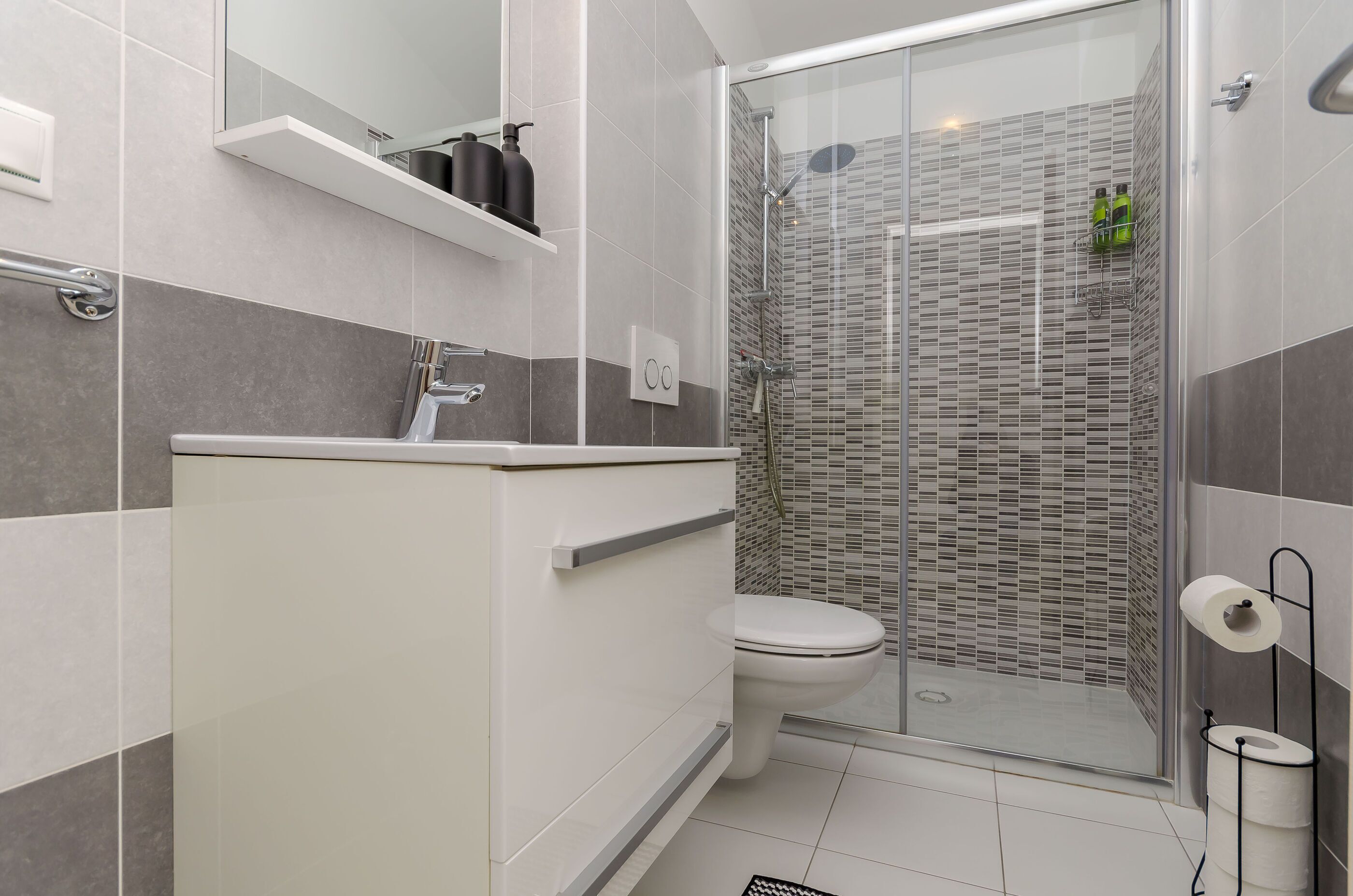 A modern bathroom with a shower, toilet, and sink.
