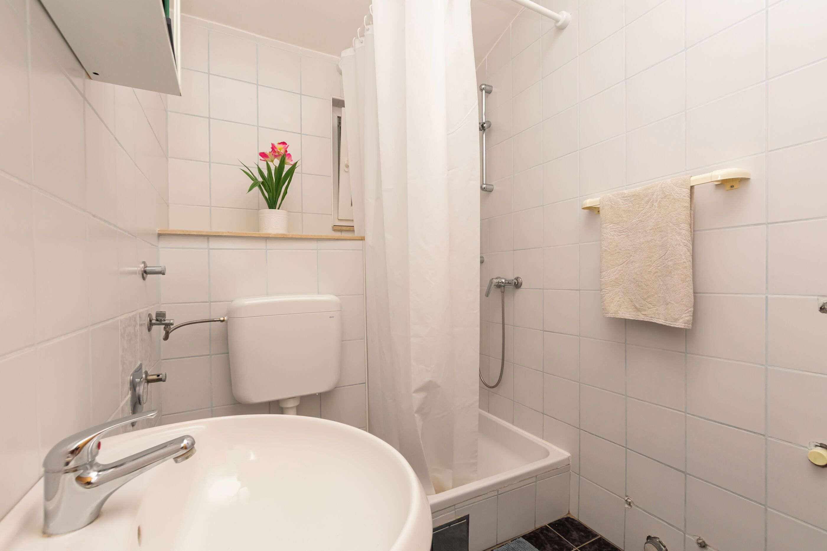Et badeværelse med hvid vask, toilet og badekar.