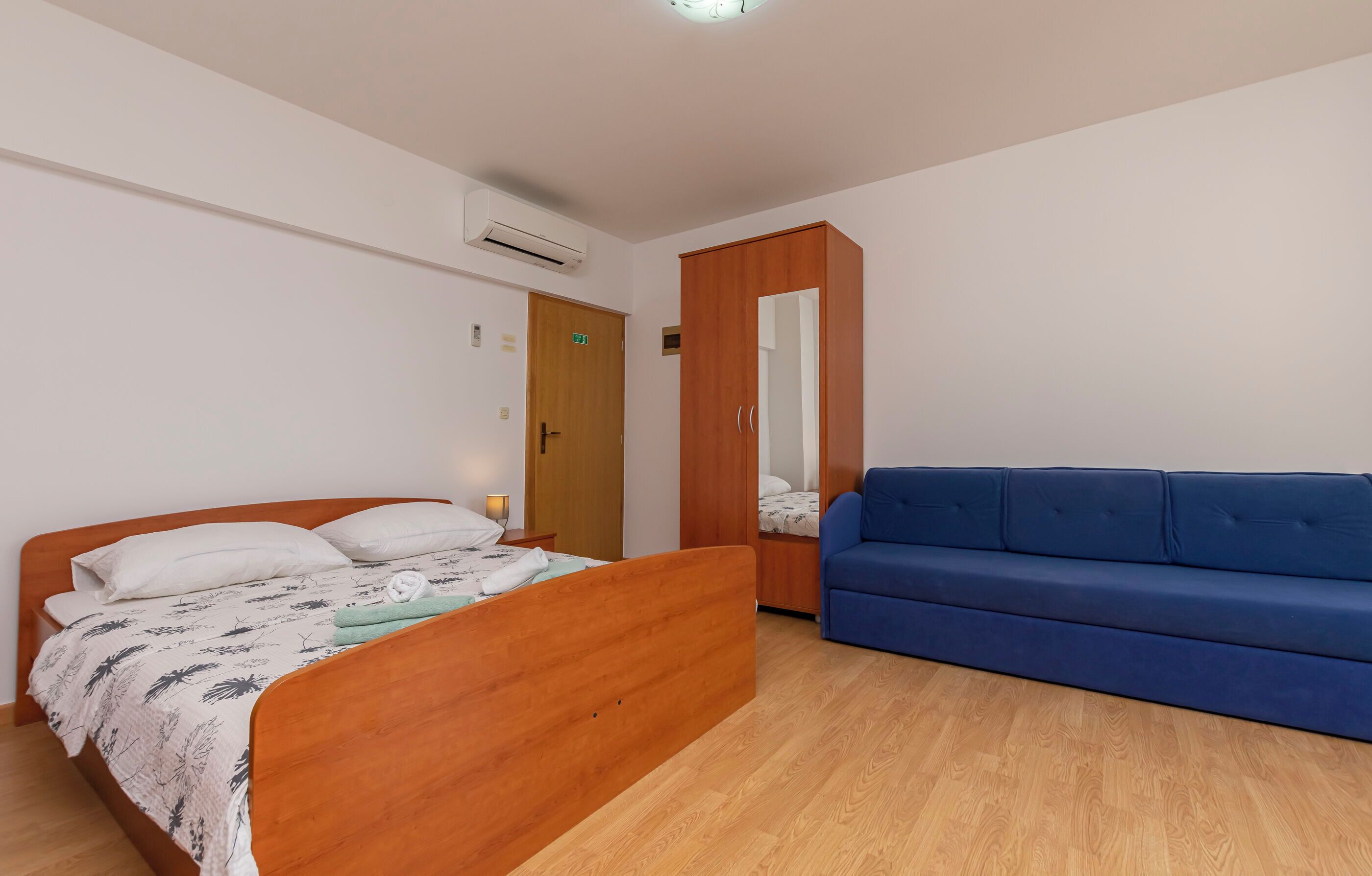 Um quarto com uma cama de madeira, um sofá azul e um guarda-roupa.